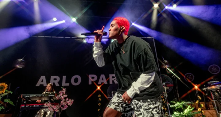 Arlo Parks performing live under stage lighting on the Ambiguous Desire era