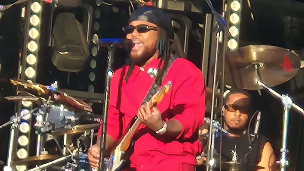 Leon Thomas performing live on stage with a guitar