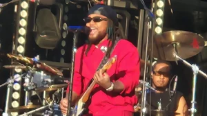 Leon Thomas performing live on stage with a guitar