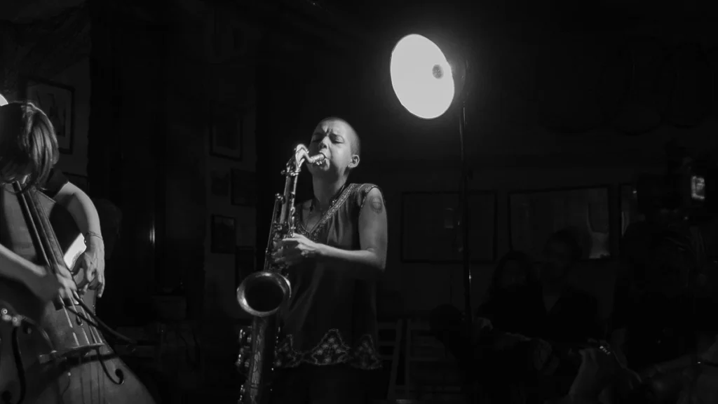 Zoh Amba performing on saxophone in an intimate venue