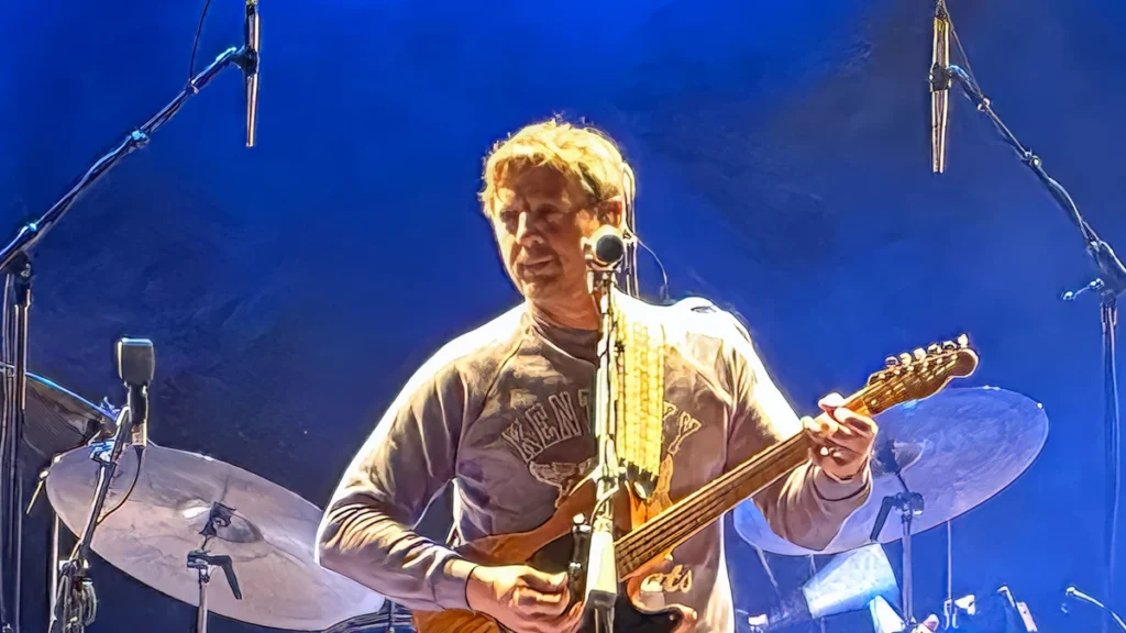 Sturgill Simpson playing guitar on stage under blue lighting