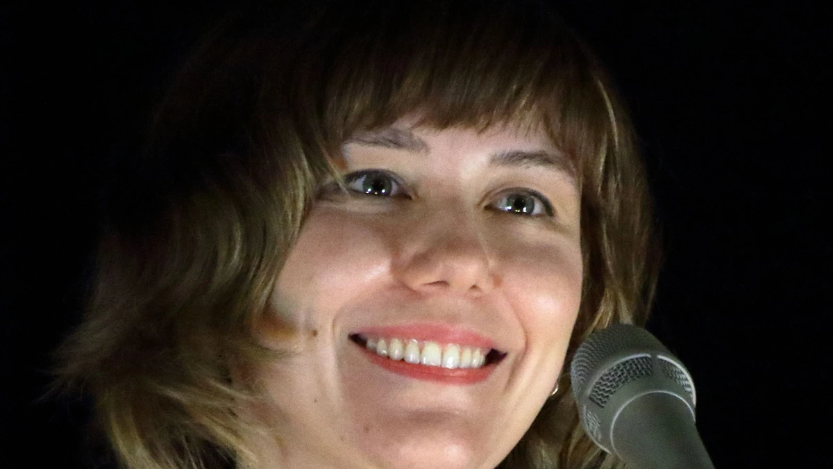 Molly Tuttle smiling beside a microphone on stage