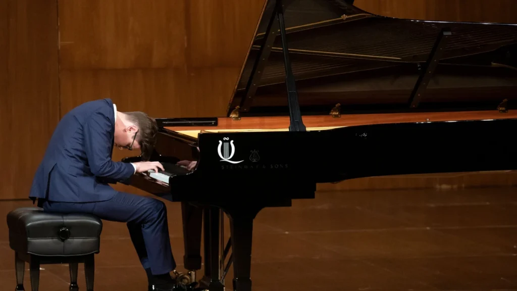 Vikingur Olafsson playing a grand piano on a concert stage