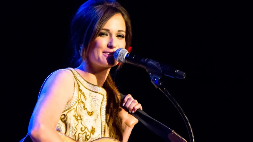 Kacey Musgraves singing into a microphone with a guitar