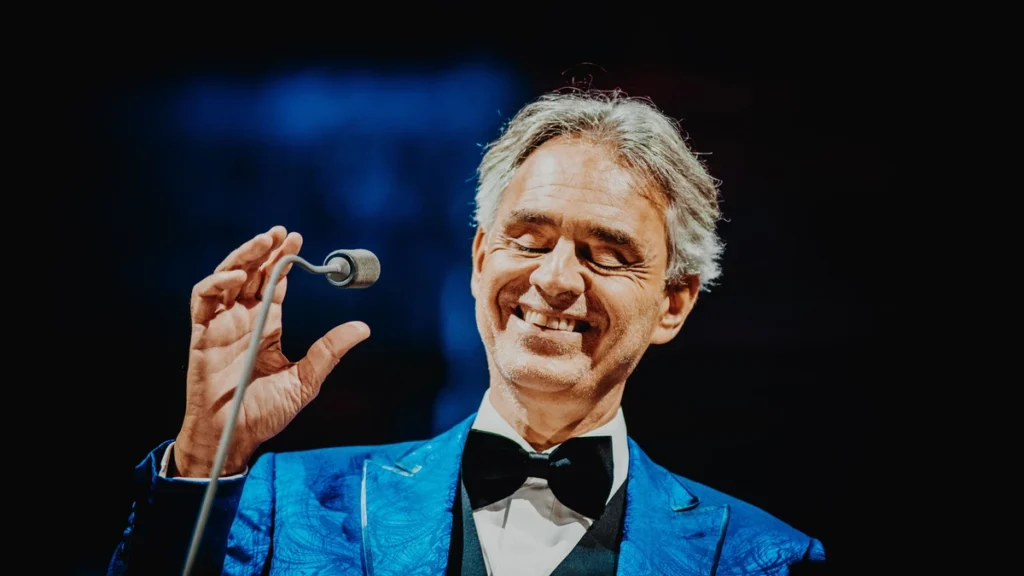 Andrea Bocelli smiling on stage in a blue jacket