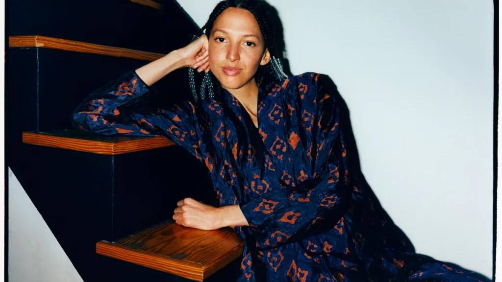 Nala Sinephro photographed seated on a staircase
