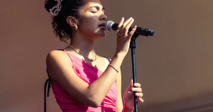 Olivia Dean singing into a microphone on stage