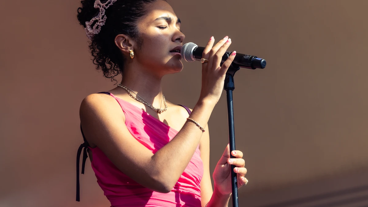 Olivia Dean singing into a microphone on stage